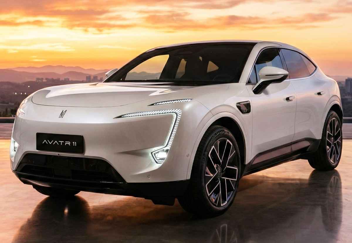 Toma frontal de tres cuartos del Avatr 11, un SUV cupé eléctrico de alta gama en color blanco. Muestra su distintiva firma lumínica LED en forma de C y su diseño aerodinámico, estacionado en una terraza moderna al atardecer. La placa delantera muestra claramente 