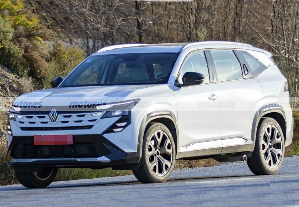 Vista frontal y lateral de la nueva Renault Boreal híbrida 4x4 blanca en fase de pruebas con camuflaje en su parrilla, rodando por una carretera europea.