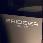 Vista de detalle a la parte trasera del nuevo SUV Renault Bridger Concept, destacando su emblema oficial plateado, la rueda de repuesto exterior y el diseño de sus luces traseras.