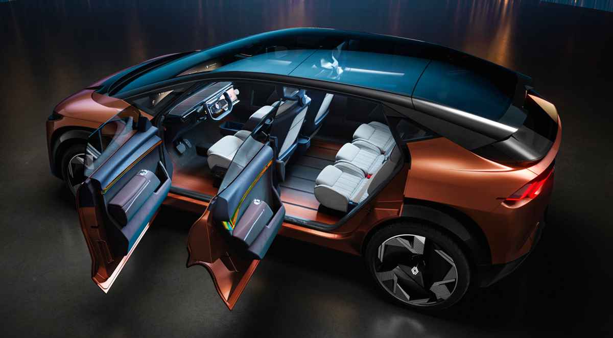 Toma cenital (vista desde arriba) con las puertas abiertas del nuevo monovolumen conceptual Renault R-Space Lab de color bronce metalizado. La imagen revela por completo el amplio habitáculo, destacando la inmensa pantalla panorámica openR que abarca el tablero, el compacto volante tipo yugo con dirección steer-by-wire y los tres asientos individuales traseros sobre un piso completamente plano. El techo de cristal continuo baña el interior con luz.