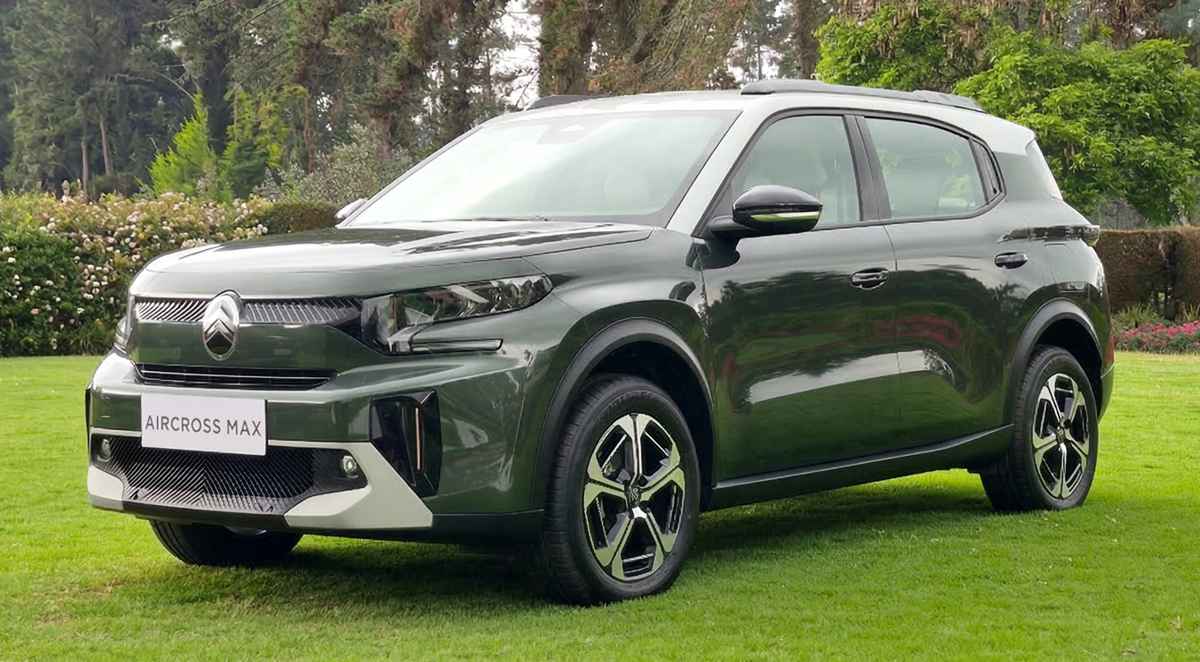 Vista de tres cuartos delantero de la nueva SUV Citroën C3 Aircross MAX Híbrida en color verde oscuro con techo blanco, estacionada sobre un prado verde. Se destacan sus faros LED en forma de C, la parrilla negra brillante con el logo de Citroën, protectores de bajos plateados y rines bitono de 17 pulgadas. El vehículo lleva una placa blanca que dice AIRCROSS MAX.