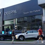 Vista exterior aérea del nuevo concesionario automotriz de Changan y Deepal en Manizales, operado por Casa López. En la entrada se exhiben varios vehículos híbridos y eléctricos de las marcas, incluyendo la pick-up Hunter y el SUV G318, con personas alrededor durante la inauguración.
