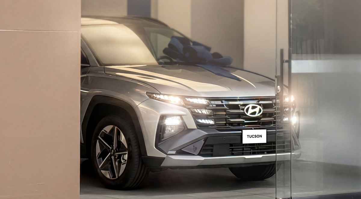 Vista lateral en primer plano de un SUV plateado Hyundai Tucson exhibido en un concesionario bien iluminado, con un moño azul de regalo sobre el capó, sugiriendo la idea de estrenar vehículo durante el evento comercial de Madiautos Bogotá.