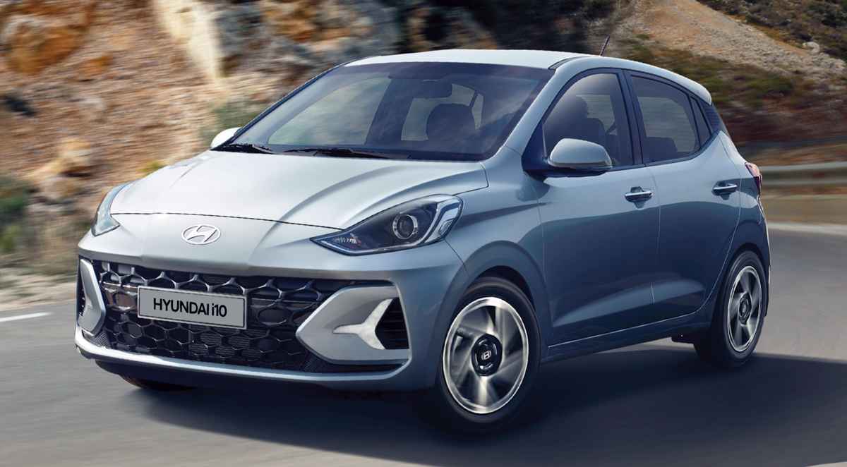 Vista frontal diagonal en movimiento del nuevo hatchback Hyundai Grand i10 color azul claro recorriendo una curva en carretera. Imagen destacada del regreso de este vehículo particular a Colombia con sus características y precios.