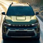 Una vista frontal superior de ángulo bajo de la nueva camioneta SUV Renault Duster de color verde oliva conduciendo por una carretera de montaña sinuosa durante un atardecer con luz dorada dramática, mostrando claramente la inscripción 