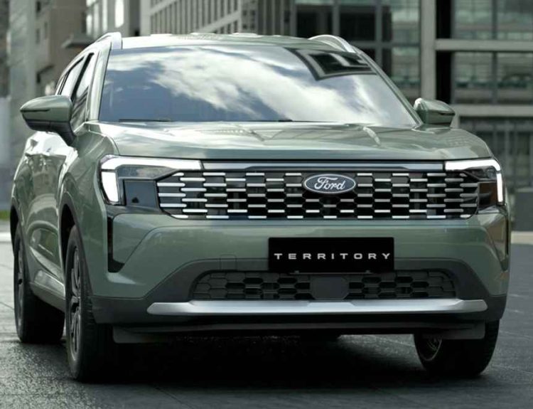 Vista frontal tres cuartos de la nueva Ford Territory Trend de color gris verdoso estacionada en una calle urbana moderna, destacando su parrilla y luces LED.