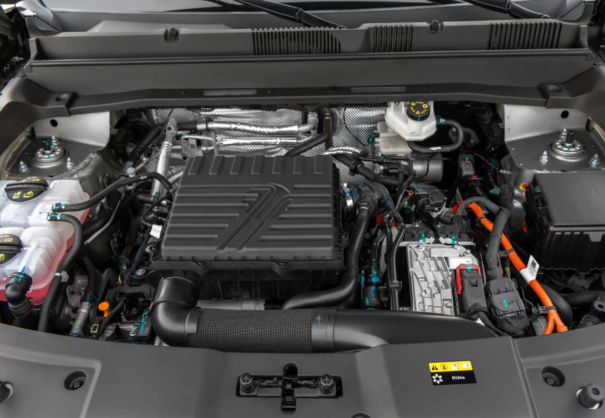 Primer plano del motor 1.5 litros turbo de la Jetour T1 i-DM híbrida enchufable bajo el capó abierto, mostrando los componentes mecánicos y cableado.