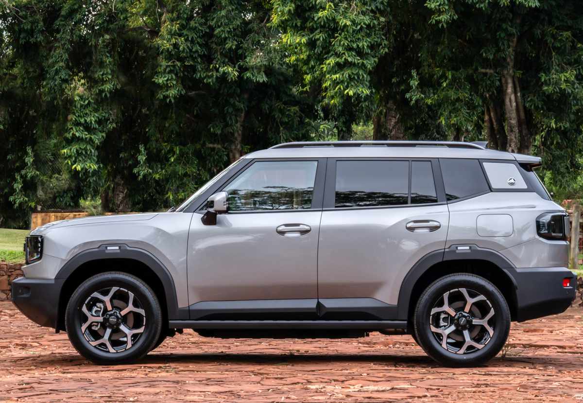 Vista lateral completa (perfil) de la SUV Jetour T1 i-DM de color gris, exhibiendo sus líneas rectas, barras de techo y rines bitono de 19 pulgadas.