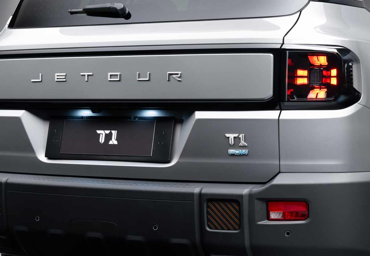 Primer plano de la compuerta trasera de la Jetour T1 i-DM, destacando las letras de la marca, el emblema de la versión híbrida y la firma lumínica LED en forma de cruz de sus faros.