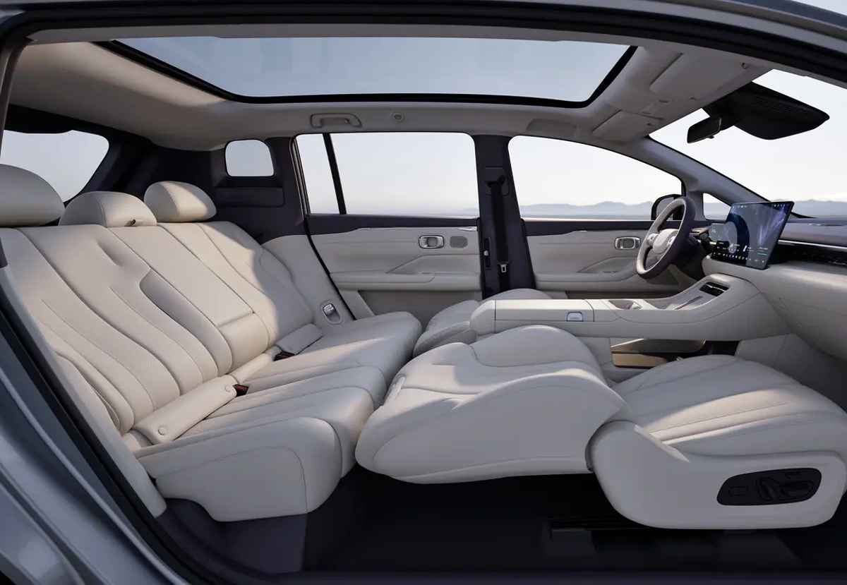 Configuración de los asientos delanteros y traseros reclinados al máximo dentro de la GAC Aion N60, mostrando el enorme espacio interior bajo el techo panorámico de cristal.
