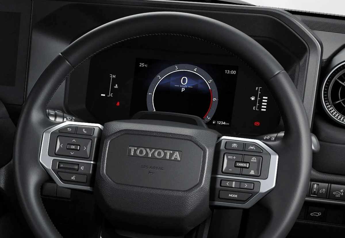 Detalle del puesto de conducción de la Toyota Land Cruiser Prado, resaltando el volante en cuero, el cuadro de instrumentos digital y las nuevas asistencias de manejo.