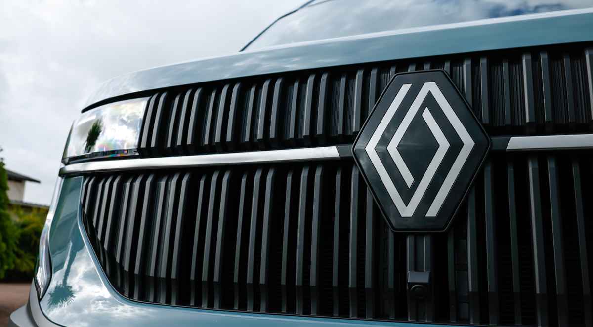 Primer plano extremo y detallado de la parrilla frontal de la nueva generación de Renault Máster, mostrando el gran emblema del rombo plateado en el centro sobre barras verticales de color gris texturizado.