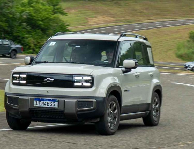 Pequeño SUV eléctrico Chevrolet Spark EUV color gris claro traza una curva rápida sobre el asfalto del Campo de Pruebas Cruz Alta en Brasil.