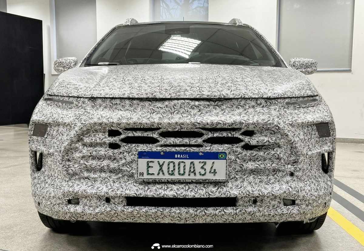 Vista frontal directa del nuevo Chevrolet Sonic camuflado en el centro técnico de General Motors en Brasil, revelando el diseño de parrilla dividida y faros en dos niveles.