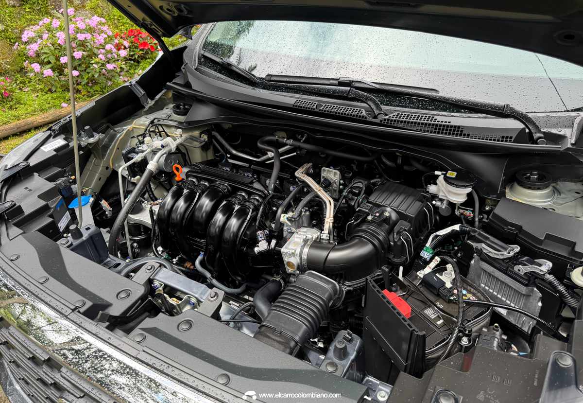 Primer plano detallado del motor a gasolina atmosférico de 1.5 litros bajo el capó abierto de la Honda WR-V, rodeado de componentes y cableado técnicos.