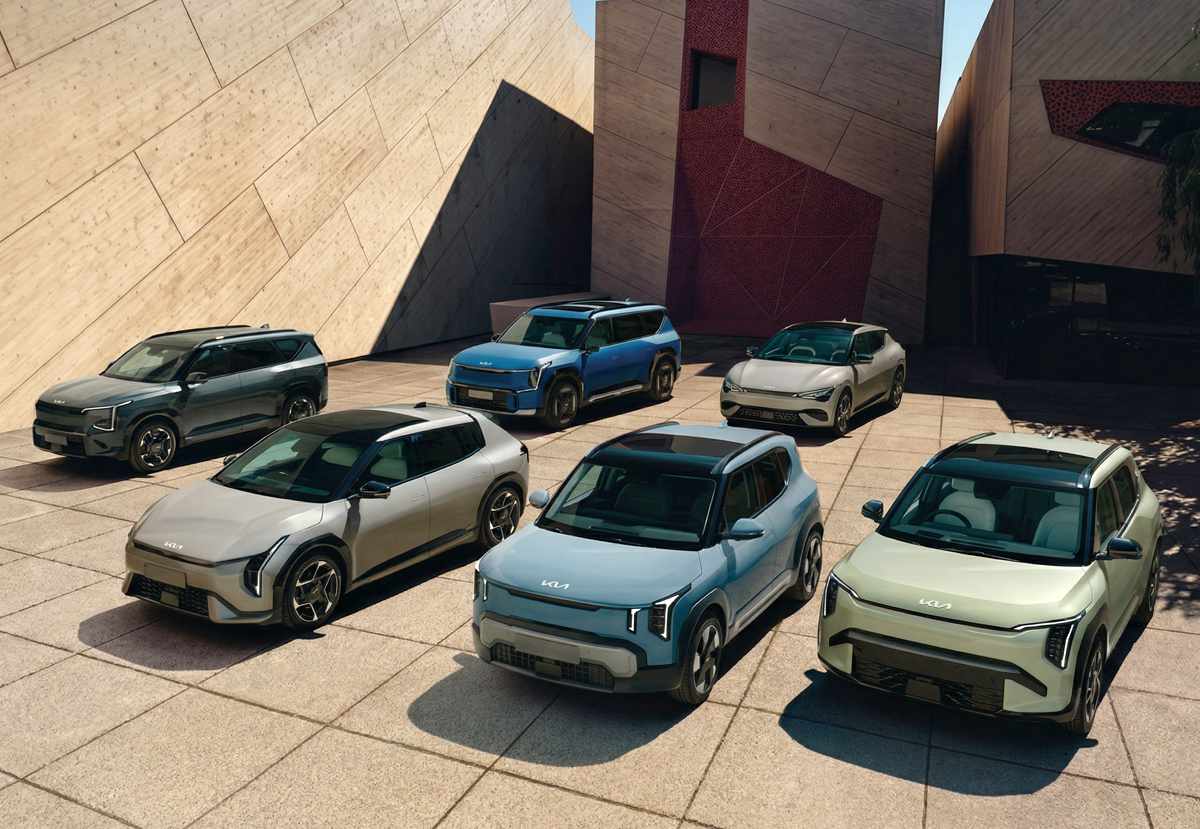 Flota completa de la nueva familia de carros eléctricos Kia estacionada sobre una plaza de arquitectura moderna, anticipando los futuros lanzamientos cero emisiones de la marca surcoreana a nivel mundial.
