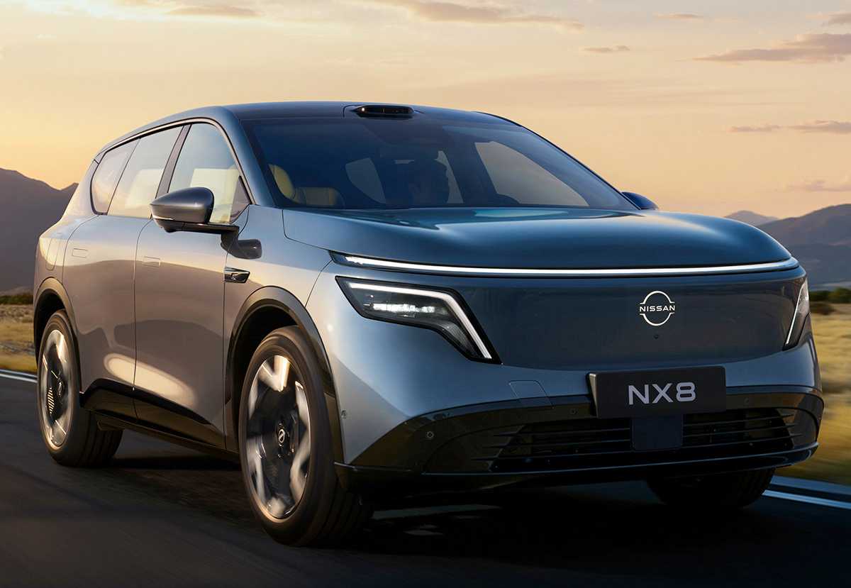 Vista frontal de tres cuartos de la SUV eléctrica Nissan NX8 color azul metalizado circulando por una carretera con un paisaje montañoso de fondo durante el atardecer.