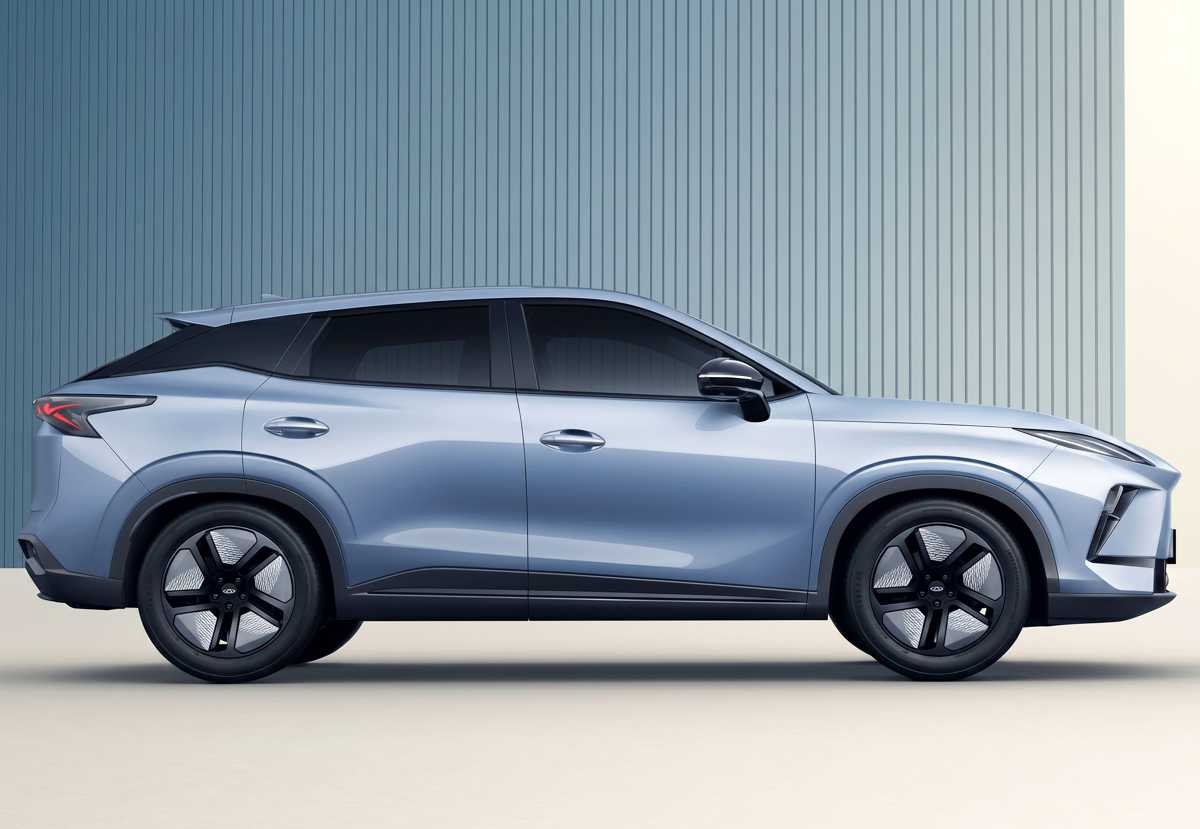 Perfil lateral completo de la nueva SUV compacta eléctrica Chery E5 color gris plata. Se aprecia su longitud, la línea del techo estilo cupé (fastback) y los grandes rines con diseño aerodinámico en negro y plata.