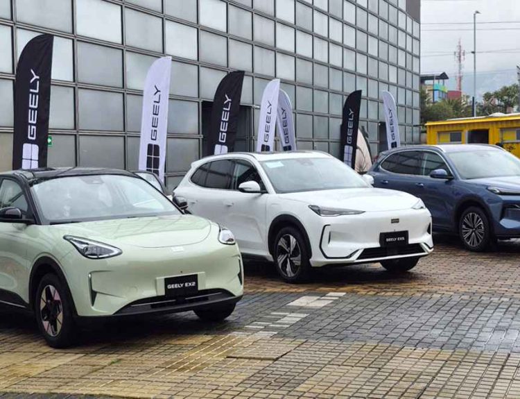 Vista frontal de la nueva línea de vehículos Geely durante su lanzamiento en Colombia. De izquierda a derecha: el city car eléctrico Geely EX2 verde claro, la SUV eléctrica Geely EX5 blanca y la SUV híbrida Geely Starray EM-i azul, estacionados junto a banderas de la marca.