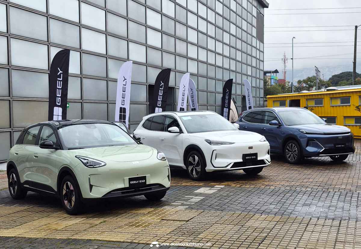 Vista frontal de la nueva línea de vehículos Geely durante su lanzamiento en Colombia. De izquierda a derecha: el city car eléctrico Geely EX2 verde claro, la SUV eléctrica Geely EX5 blanca y la SUV híbrida Geely Starray EM-i azul, estacionados junto a banderas de la marca.