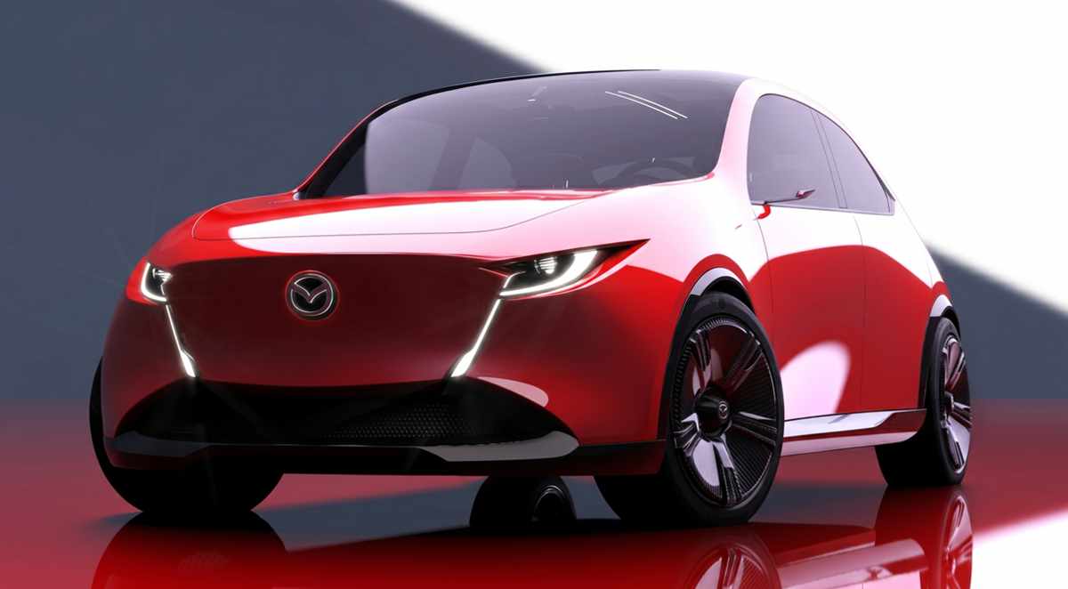 Vista frontal de estudio del concept car Mazda Vision X-Compact, un prototipo bicolor rojo y blanco con diseño Kodo evolucionado. Muestra faros LED delgados integrados en una moldura que forma una 'V' alrededor del emblema de la marca, rines oscuros de gran tamaño y una postura baja y ancha. Esta imagen anticipa el futuro diseño de los próximos Mazda 2 y CX-3.