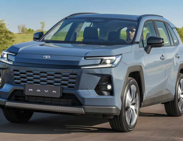 Vista frontal de tres cuartos de la nueva SUV híbrida Toyota RAV4 2026 color azul metálico circulando por una carretera, mostrando su renovada parrilla y faros LED diurnos.