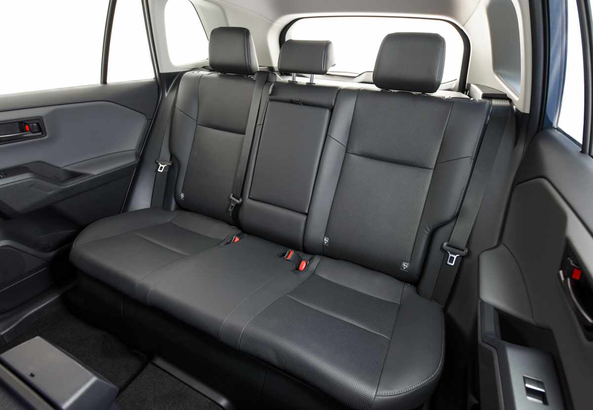 Vista de la segunda fila de asientos en el interior de la Toyota RAV4, mostrando la tapicería oscura, los tres apoyacabezas y el espacio disponible para los pasajeros.
