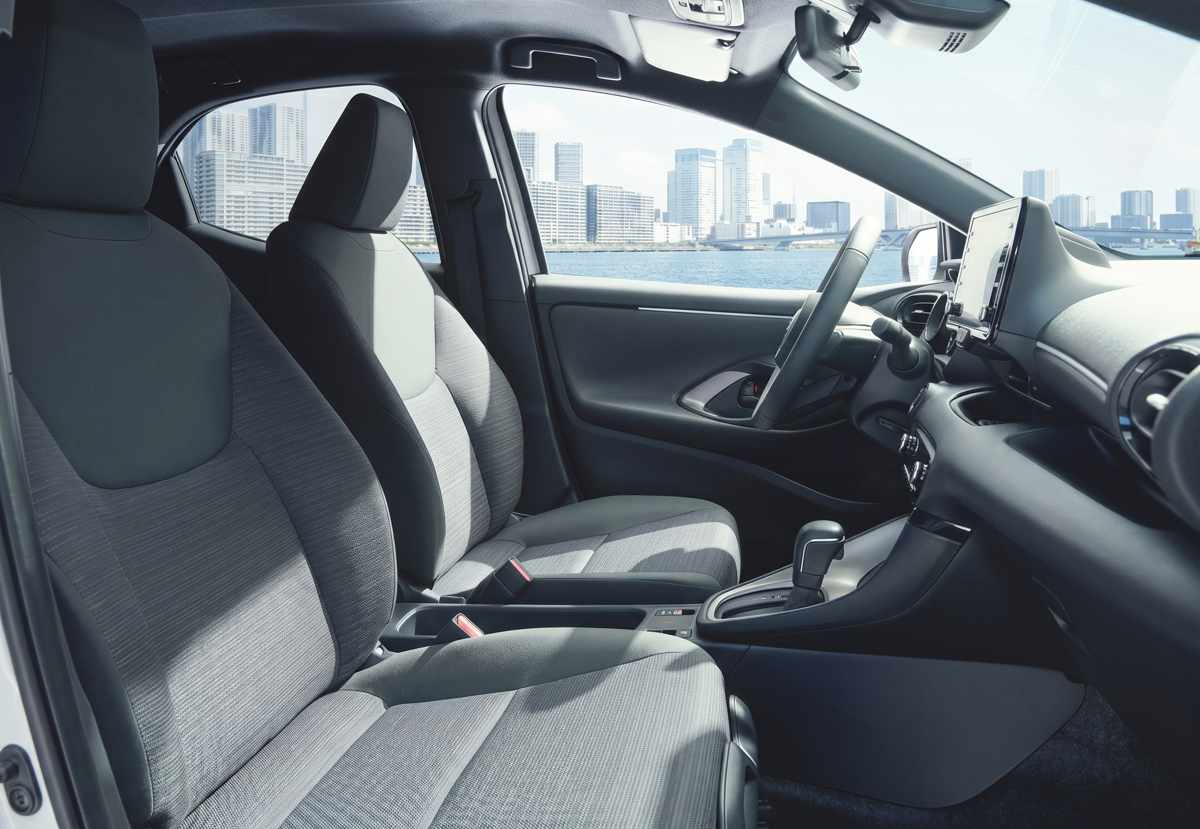 Primer plano de los asientos delanteros de un Toyota Yaris, mostrando la tapicería de tela con un patrón geométrico de panal y costuras grises.
