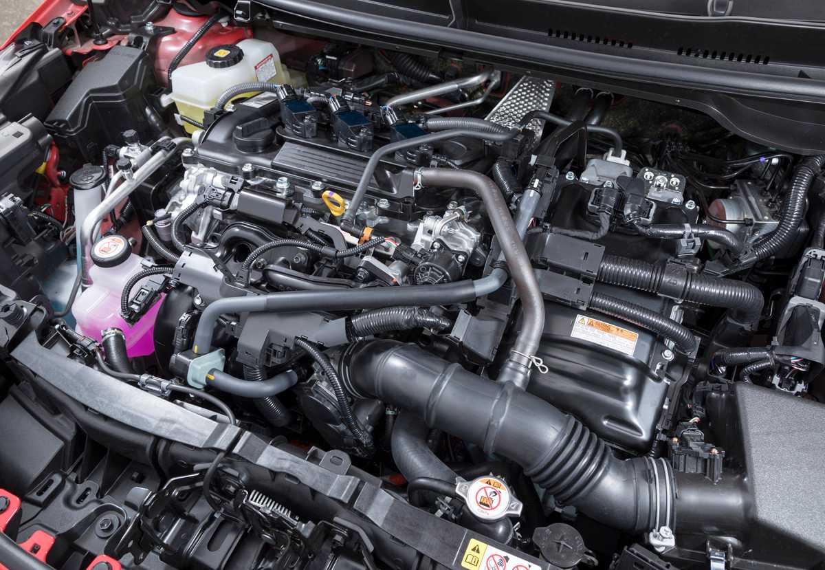 Vista detallada del compartimento del motor de un Toyota Yaris híbrido, mostrando el motor de tres cilindros y 1.5 litros, componentes del sistema híbrido con el emblema 'HYBRID SYNERGY DRIVE' y cableado.