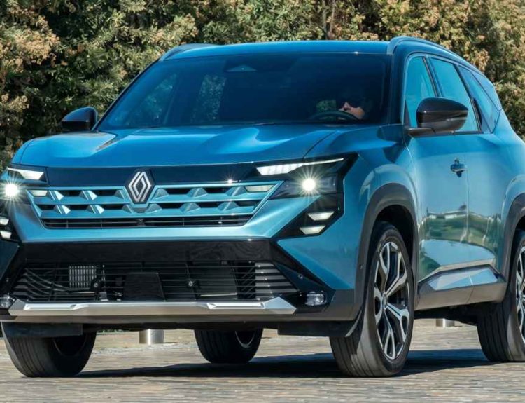 Vista frontal de tres cuartos de la nueva camioneta mediana Renault Boreal en color azul metálico. El vehículo se encuentra estacionado en una zona pavimentada en un día soleado, con árboles verdes de fondo. Se aprecian detalladamente los modernos faros LED en forma de C encendidos, la renovada parrilla frontal con el nuevo logotipo del rombo en el centro y los rines de aleación bitono, mostrando el diseño robusto que llegará a Colombia.