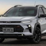 Vista tres cuartos delantera del nuevo crossover Chevrolet Sonic 2027 plateado estacionado, mostrando faros LED principales, luces diurnas superiores divididas, parrilla superior negra con el nuevo logotipo oscuro de la marca, parrilla inferior con emblema 