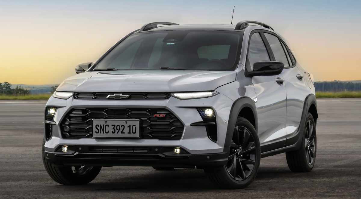 Vista tres cuartos delantera del nuevo crossover Chevrolet Sonic 2027 plateado estacionado, mostrando faros LED principales, luces diurnas superiores divididas, parrilla superior negra con el nuevo logotipo oscuro de la marca, parrilla inferior con emblema 