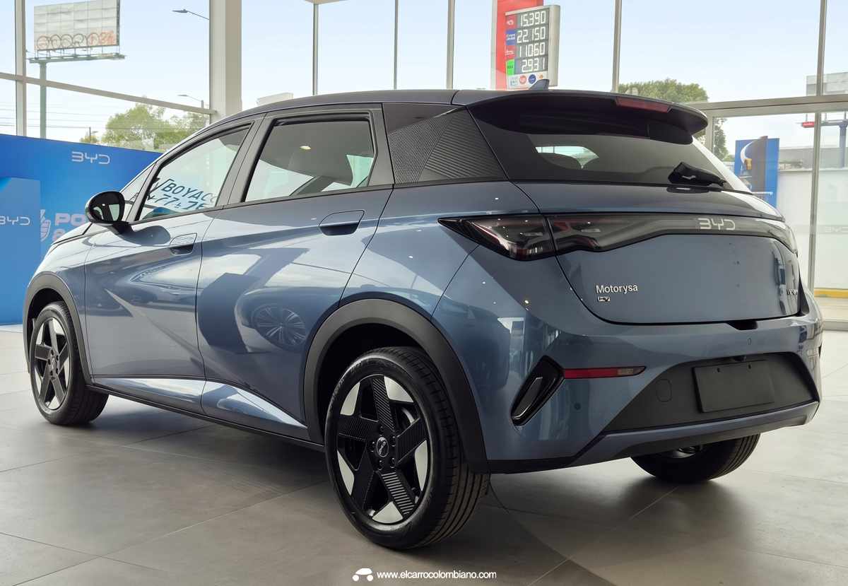 Vista tres cuartos trasera del nuevo BYD Dolphin 2026 color azul exhibido en concesionario, detallando la nueva firma lumínica LED horizontal, el alerón superior y el baúl de 250 litros.