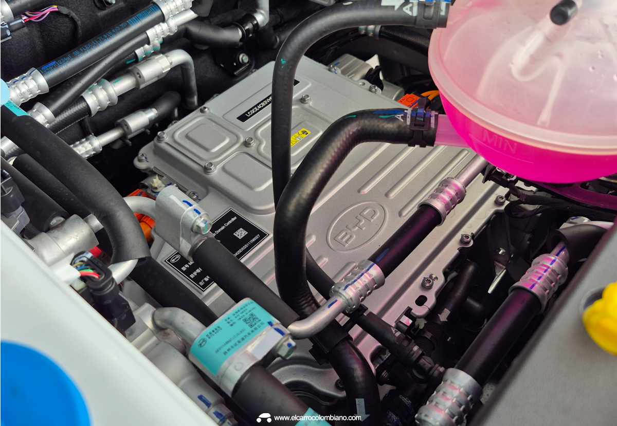 Vista detallada del compartimiento mecánico del nuevo BYD Dolphin 2026, mostrando los componentes del renovado motor eléctrico delantero de 177 hp bajo una cubierta plateada con el emblema BYD.