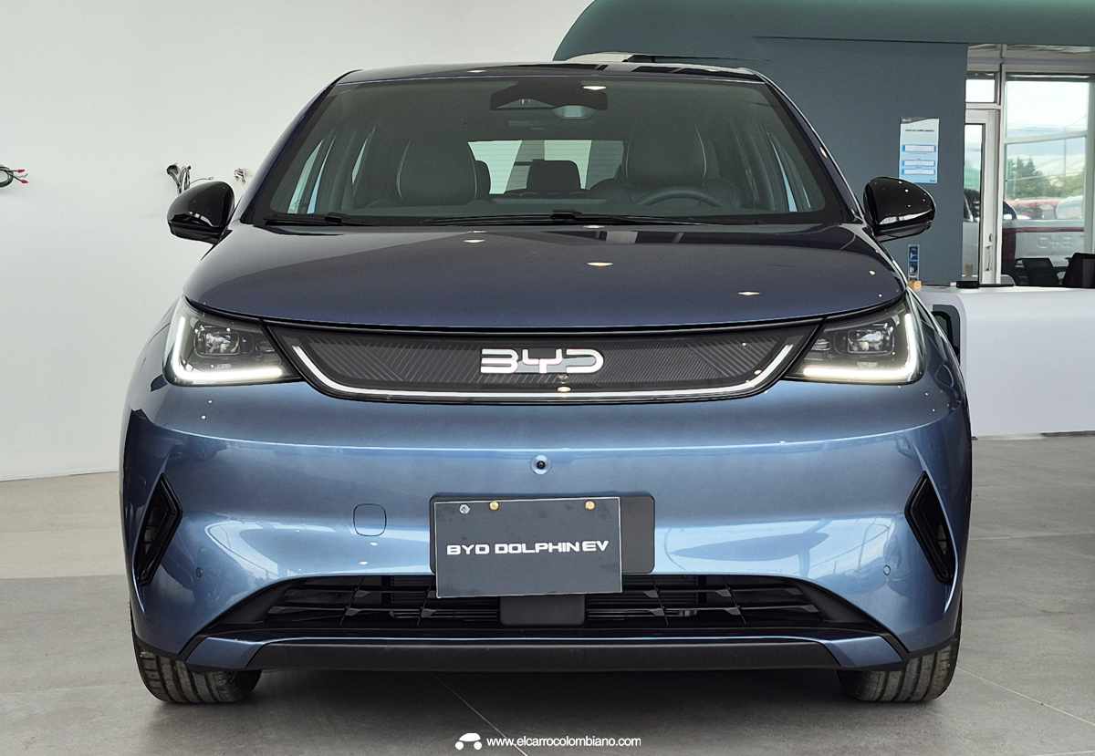 Vista frontal directa del nuevo BYD Dolphin 2026 color azul, resaltando el emblema central de la marca ahora iluminado y la franja oscura que conecta los faros LED principales.