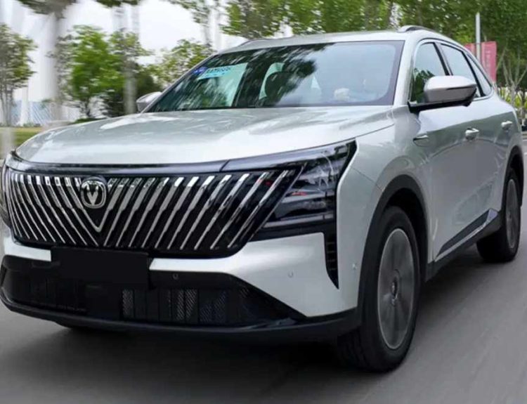 Vista tres cuartos delantera de la nueva Changan CS75 Plus HEV plateada en movimiento sobre una avenida, destacando su enorme parrilla frontal con barras inclinadas.