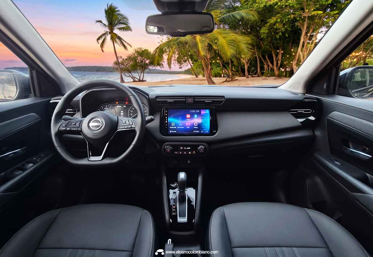 Vista del tablero y el interior frontal de la SUV Nissan Kait desde la posición del conductor, destacando el volante multifunción, el cuadro de instrumentos y la pantalla táctil central que muestra una imagen de playa y el texto 
