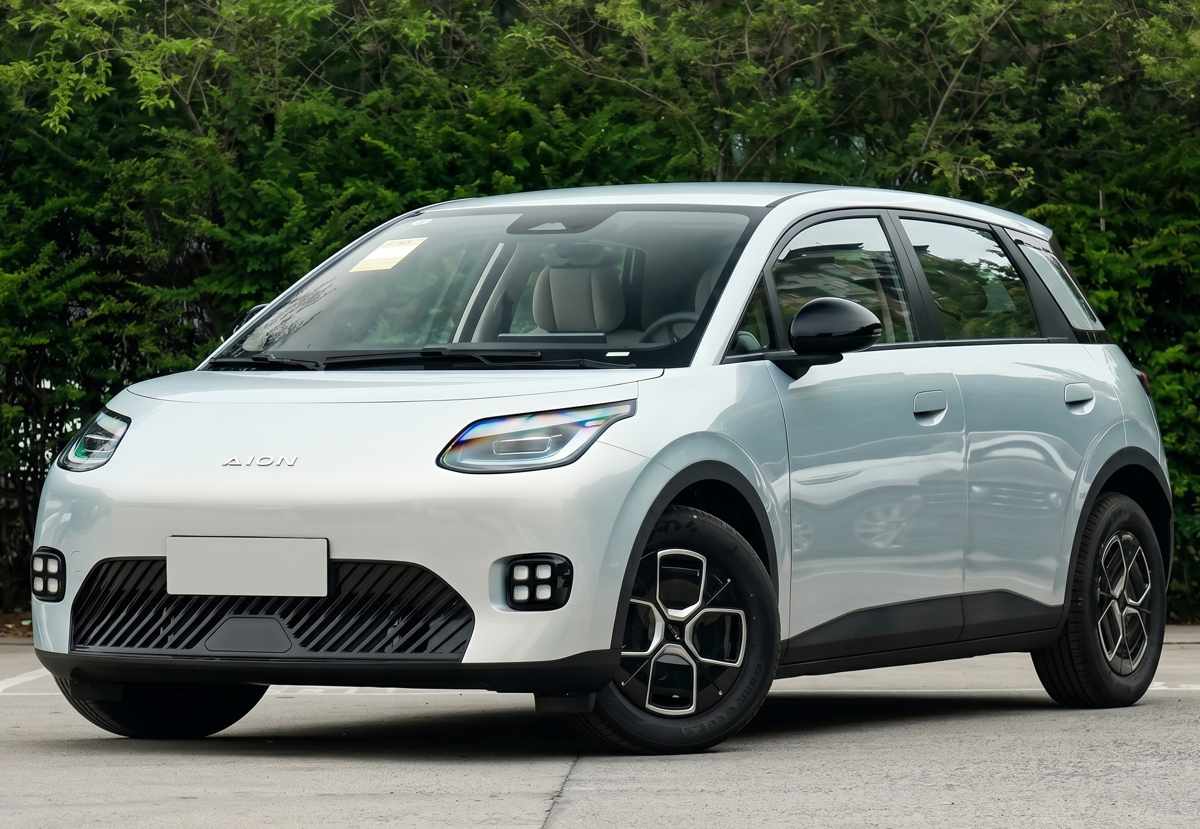 Vista frontal de tres cuartos del hatchback eléctrico compacto GAC Aion UT en color blanco plateado, estacionado al aire libre. Exhibe su diseño urbano redondeado, rines aerodinámicos y faros delanteros ovalados, perfilándose como el modelo de entrada de la marca.
