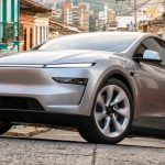 Camioneta eléctrica Tesla Model Y de color plateado, estacionada sobre una calle empedrada rodeada de arquitectura tradicional colombiana con fachadas coloridas y balcones. Este modelo se consolidó como el carro más vendido de Colombia durante abril de 2026.