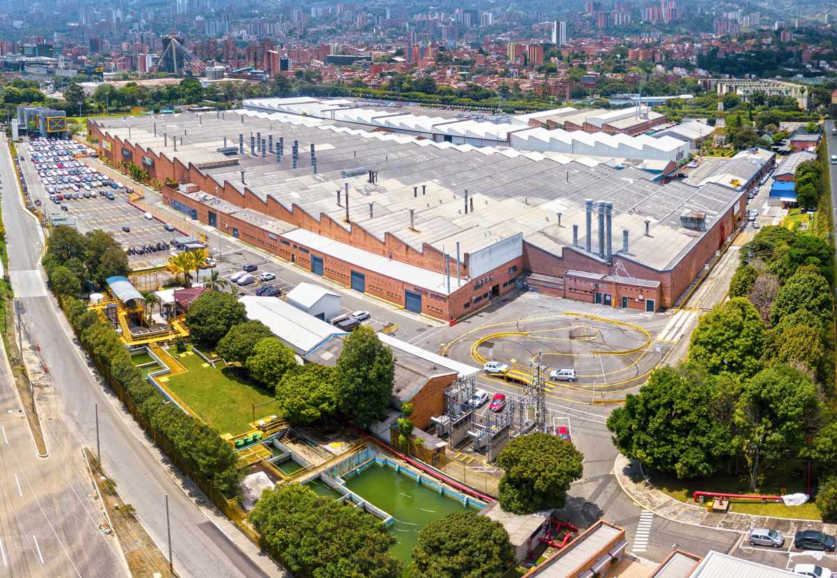Vista aérea panorámica del gran complejo industrial de ensamblaje de Renault-Sofasa ubicado en Envigado, Antioquia, destacando sus extensas naves de producción con techos aserrados, parqueaderos y pista de pruebas.