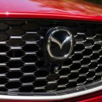 Primer plano de la parrilla frontal negra y el logotipo cromado de Mazda en un vehículo color rojo, ilustrando el misterio sobre el reciente registro comercial del nombre CX-40 para un posible nuevo SUV.