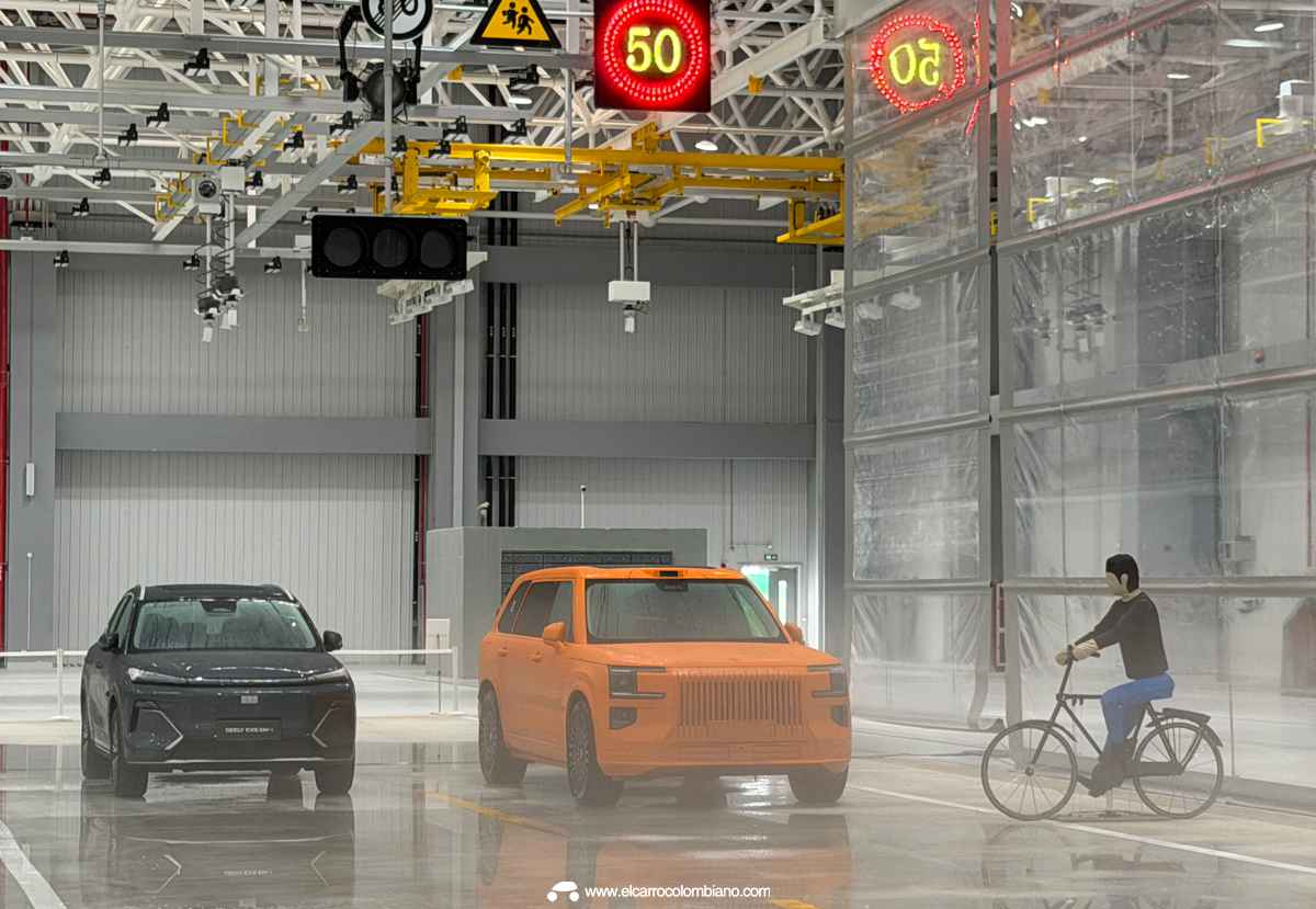 Simulación de sistemas de seguridad activa en el laboratorio bajo techo de Geely. Un maniquí sobre una bicicleta se cruza frente a dos modernos vehículos SUV Geely Starray y Zeekr 9X, probando las tecnologías de detección de peatones y frenado autónomo de emergencia bajo estrictas condiciones controladas.
