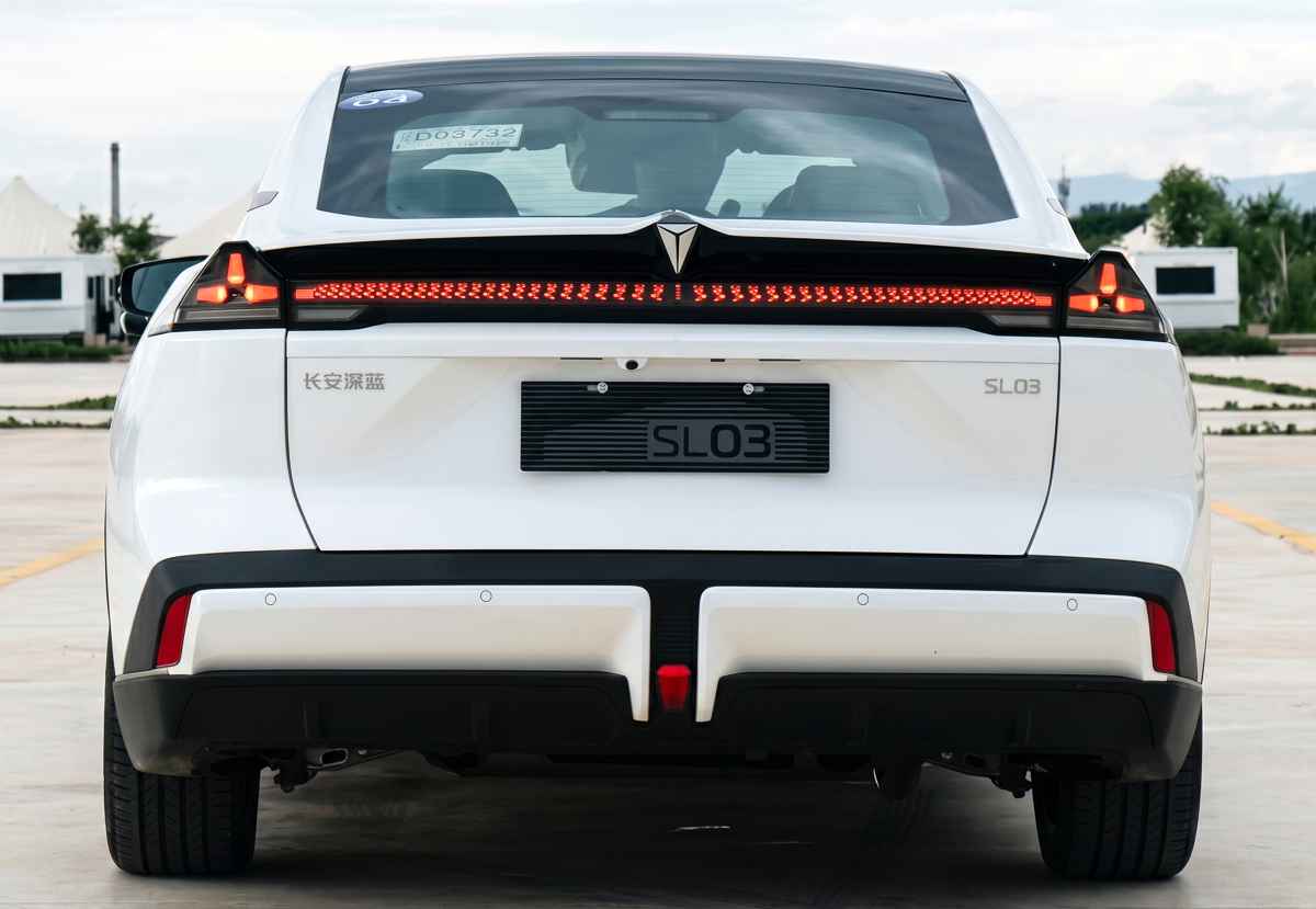 Diseño posterior del Deepal SL03 color blanco. Resalta su firma lumínica con una franja LED roja que atraviesa el maletero de lado a lado, luces de freno triangulares en los extremos, el logo de la marca iluminado al centro y un parachoques inferior negro con difusor de estilo deportivo.