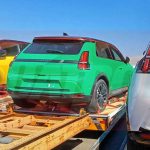 Foto espía del nuevo Renault 5 eléctrico desembarcando en el aeropuerto de Viracopos, Brasil. Se observa la parte trasera de una unidad color verde intenso sobre una grúa de plataforma, acompañada de otras unidades en colores amarillo y blanco, confirmando su llegada a Sudamérica.