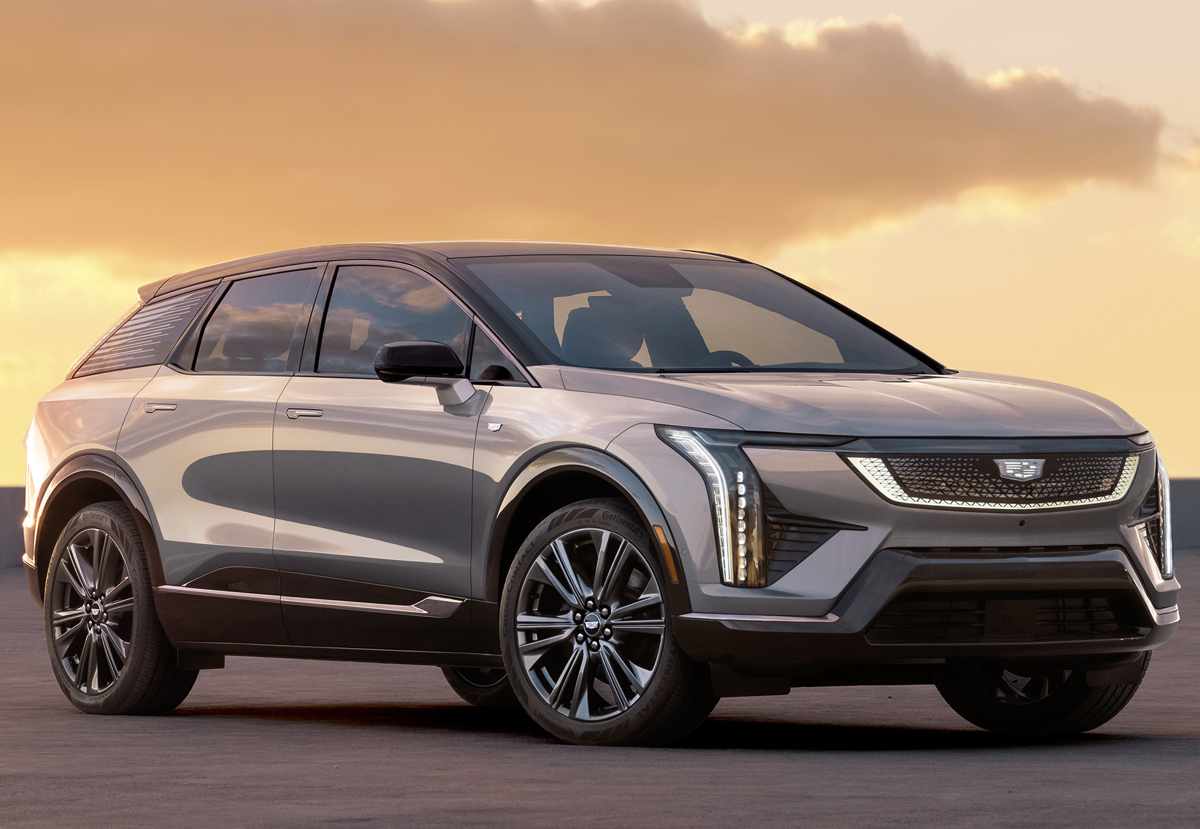 Vista en tres cuartos frontal de la SUV eléctrica Cadillac Optiq color plata. Resalta su diseño aerodinámico, rines bitono y una parrilla negra brillante enmarcada por la característica firma lumínica vertical de la marca.