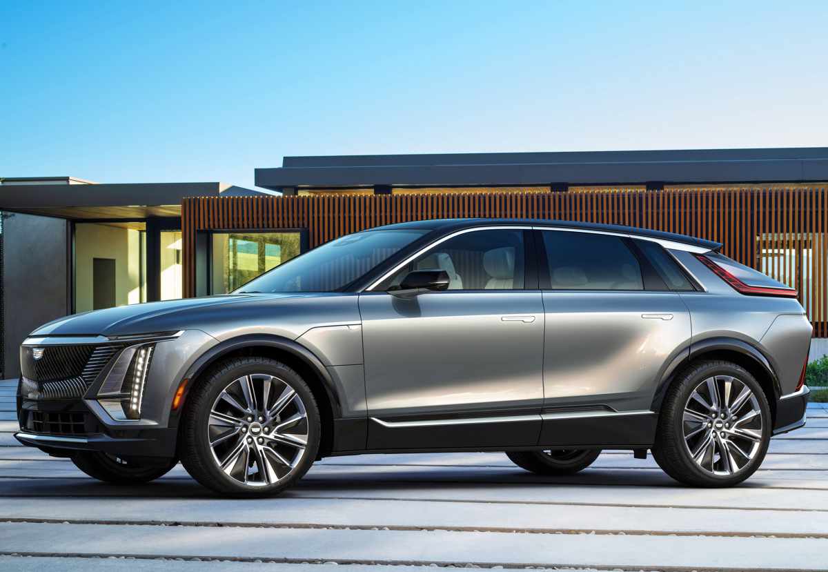 Perfil lateral del enorme sedán eléctrico Cadillac Lyriq color plata brillante. Resalta su extensa distancia entre ejes, líneas fluidas y un diseño futurista aerodinámico sin manijas tradicionales a la vista en las puertas.