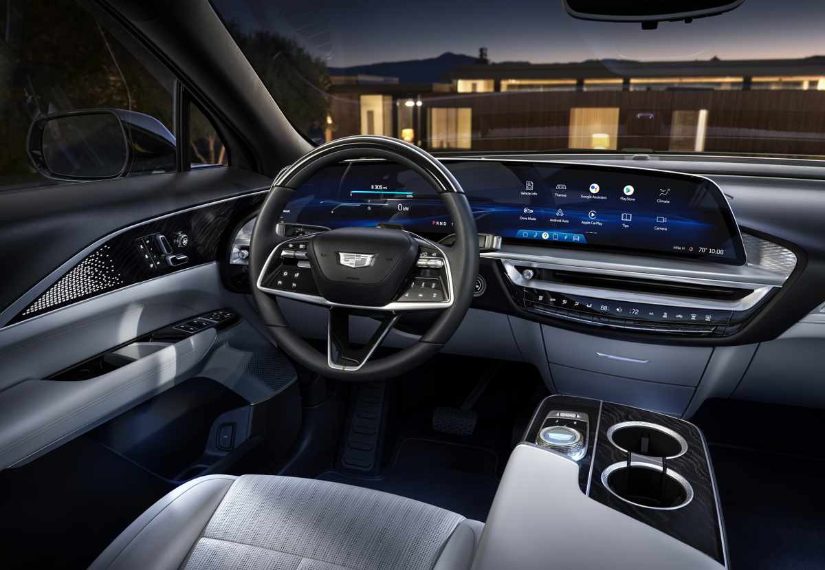 Vista detallada del interior de un moderno vehículo eléctrico Cadillac Lyriq. El protagonismo se lo lleva una gigantesca pantalla digital curva de alta definición que domina el tablero, combinada con acabados premium en aluminio y cuero claro.