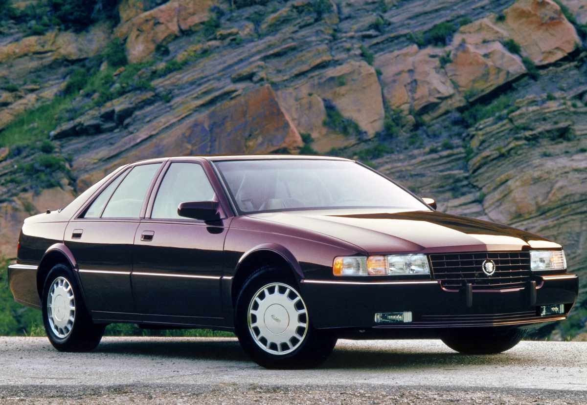 Fotografía de archivo de un clásico sedán Cadillac Seville de principios de los años 90 en color rojo oscuro. Representa la época histórica en que la marca importó oficialmente estos vehículos de lujo a Colombia tras la apertura económica.