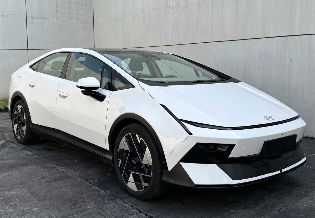 Fotografía frontal de registro del nuevo sedán Hyundai Ioniq V color blanco. Destaca su diseño tipo fastback con líneas afiladas, faros delgados integrados, rines aerodinámicos bitono y un robusto parachoques inferior negro mate.