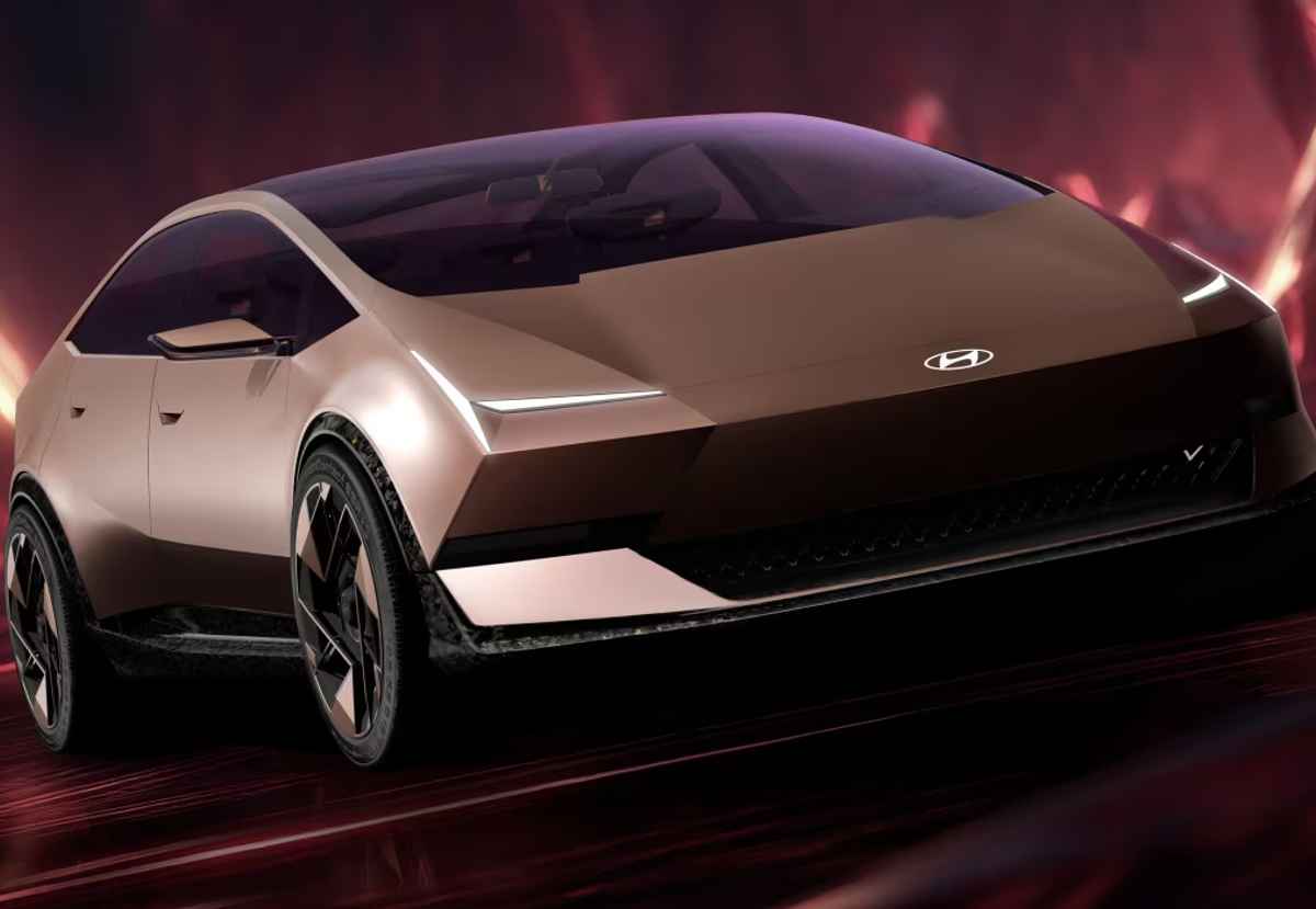 Render oficial del diseño exterior futurista del Hyundai Ioniq V (Hyundai Venus Concept) en un elegante tono bronce brillante. Exhibe una silueta aerodinámica, capó liso y faros LED en forma de cuña, transmitiendo una imagen altamente tecnológica.